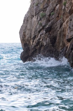 Kayalık sahilde güçlü dalgalar, kayalara çarpan dalgalar.