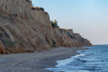 Karadeniz kıyısı, sahildeki manzara, kumlu uçurum ve güneşli yaz gününde tek bulutlu mavi gökyüzü. Sanzhiika, Odessa bölgesi, Ukrayna.