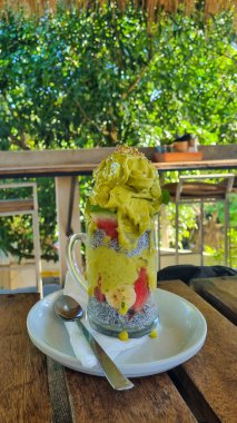 Nar, kivi, elma ve üzümle kaplı cam bardaklarda Chia tohumu pudingi veya chia meyveli muhallebi. Canlı bir vejetaryen tatlı, taze meyve, chia tohumu ve sağlık görselleri için kırsal stil.