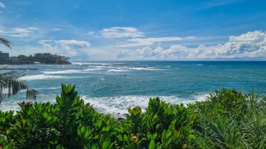 Yumuşak altın kumları ve bereketli yeşilliklerle çerçevelenmiş turkuaz suları olan güzel tropikal plajlar. Huzurlu okyanus manzarası ve canlı renkler onu tatil ve rahatlama için mükemmel bir yer yapıyor.