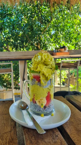 Nar, kivi, elma ve üzümle kaplı cam bardaklarda Chia tohumu pudingi veya chia meyveli muhallebi. Canlı bir vejetaryen tatlı, taze meyve, chia tohumu ve sağlık görselleri için kırsal stil.