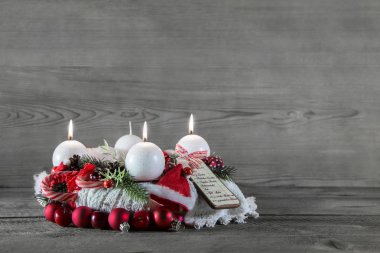 Kırmızı ve beyaz gri ahşap üzerinde üç mum ile Advent taç 