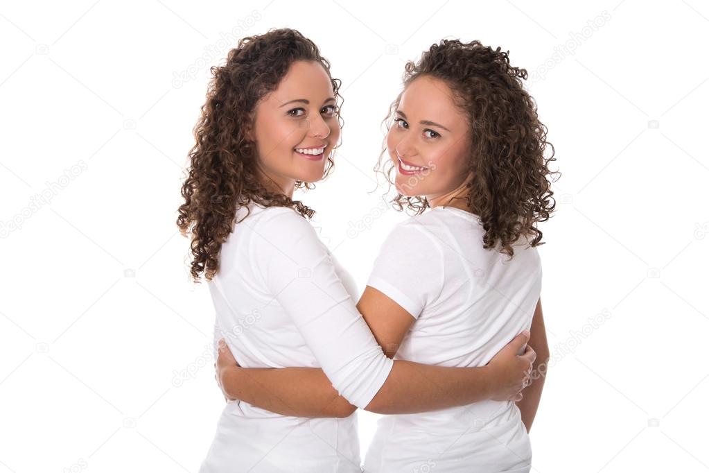 Portrait of real twin sisters isolated over white.