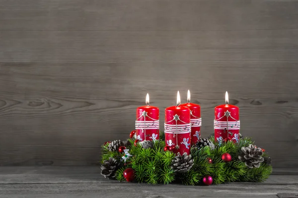 Corona de Adviento o corona con cuatro velas rojas sobre fondo de madera — Foto de Stock