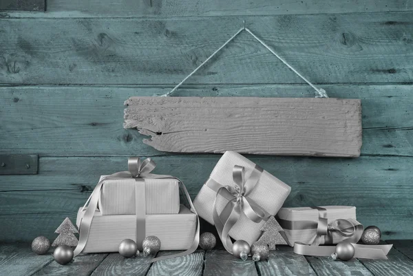 Ασημένια χριστουγεννιάτικα δώρα σε ξύλινα φόντο με ένα σημάδι. — Φωτογραφία Αρχείου