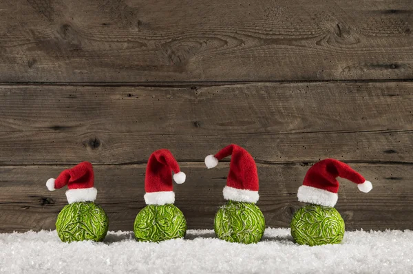 Funny christmas background with green balls and santa hats on wo — Stock Photo, Image