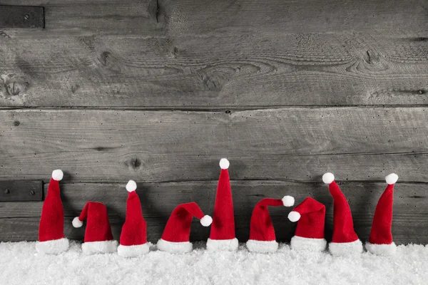 Wooden christmas background with red santa hats for a festive fr — Stock Photo, Image
