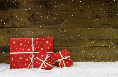 Kar taneleri ile ahşap arka plan üzerinde kırmızı Noel hediyeleri.