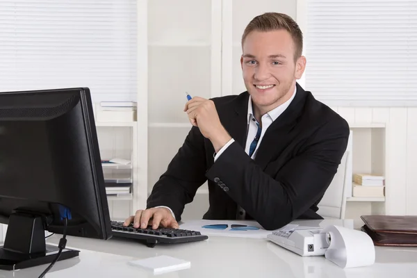 Porträt: Schöner junger Geschäftsmann im Anzug sitzt lächelnd in — Stockfoto