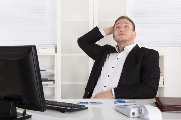 Pensativo joven soñando hombre de negocios sentado en el escritorio mirando hacia arriba . — Foto de Stock