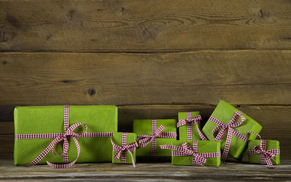 Apfelgrüne Geschenke mit rot-weiß kariertem Band auf Holz — Stockfoto