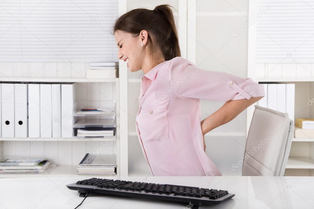 Young woman sitting with backache in the office.