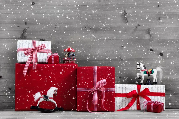 Rote Weihnachtsgeschenke und Geschenkboxen mit Schaukelpferd auf grau — Stockfoto