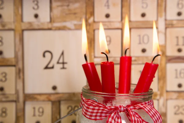 Cuatro velas rojas de adviento ardientes con calendario . — Foto de Stock