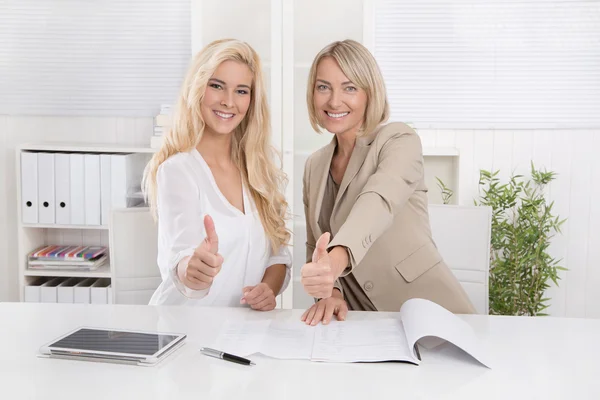 Две улыбающиеся блондинки-бизнесвумен, работающие в команде, рекомендуют Фину — стоковое фото
