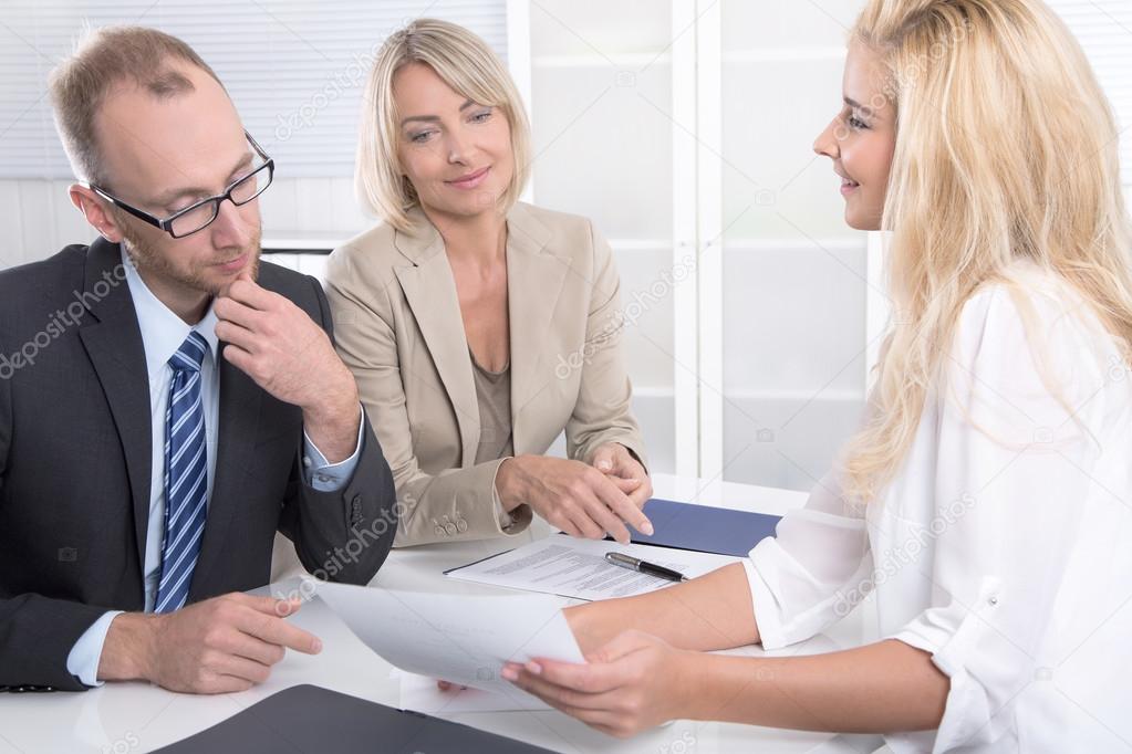 Business team of man an woman sitting around a table talking tog