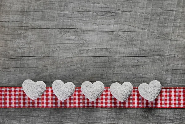 Cinco corações brancos em um fundo de madeira cinza velho com uma xadrez — Fotografia de Stock