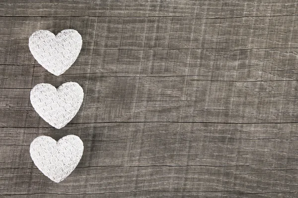 Trois cœurs blancs sur un vieux fond en bois brun gris . — Photo