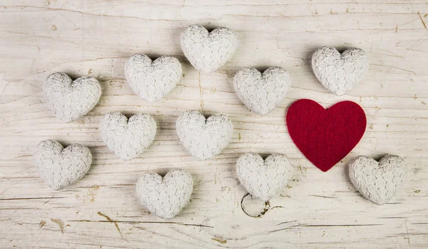 One red heart in a collection of many white hearts on an old sha — Stock Photo, Image