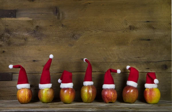 Tarjeta de felicitación divertida de Navidad con siete sombreros rojos de santa en la manzana — Foto de Stock