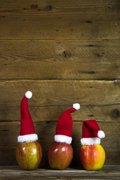 Tarjeta de felicitación de Navidad con tres sombreros rojos de santa en manzanas con —  Fotos de Stock