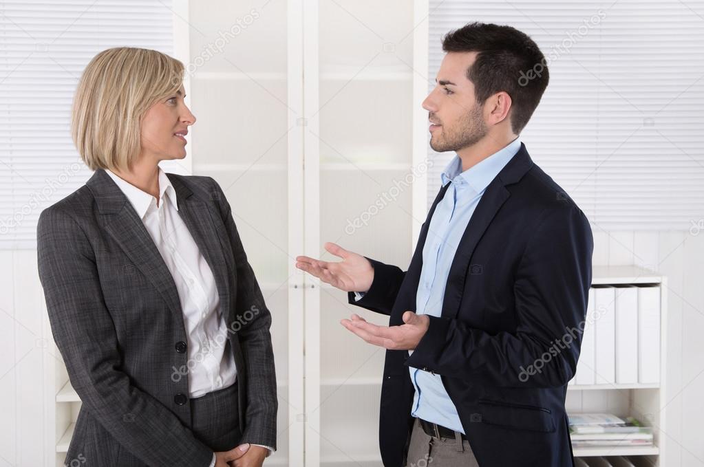 Two business people working in a team talking together in the of