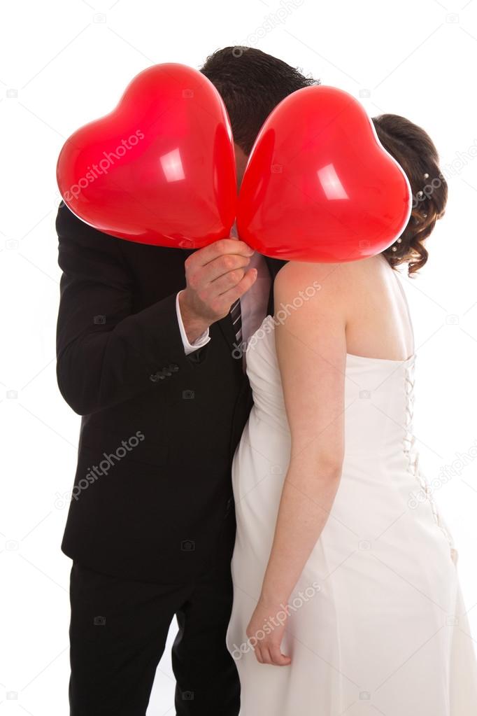 Kissing bridal pair with red heart ballons isolated over white.