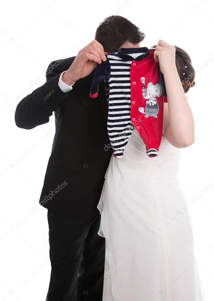 Kissing wedding couple with baby clothes: pregnancy and marriage