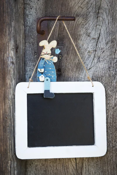 Yazı tahtası ve geçici adver üzerinde oturan mavi ahşap Paskalya tavşanı — Stok fotoğraf