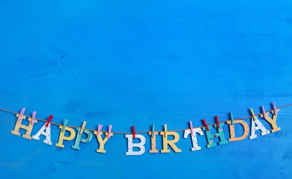 Blauwe achtergrond met kleurrijke houten opknoping letters op een clothe — Stockfoto
