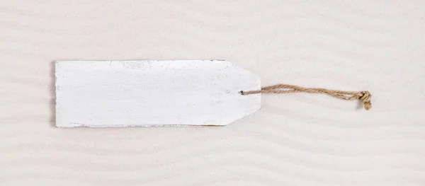 Gammel, hvit treetikett eller skilt i beige sand . – stockfoto