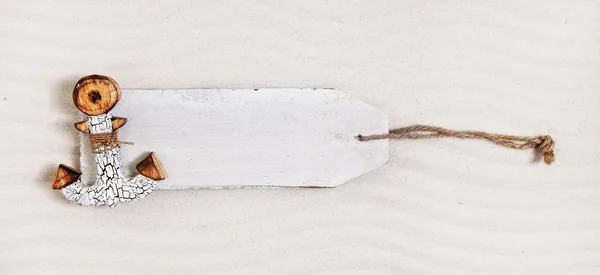 Weißes Holzschild mit einem Anker im Sand. Werbetafel — Stockfoto