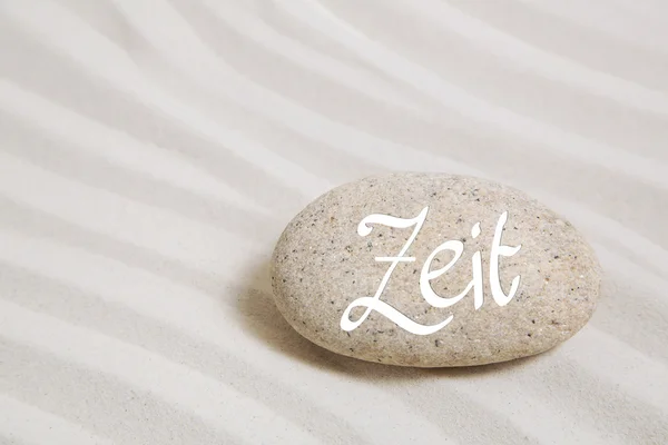 Stein im Sand mit deutschem Text: Zeit. Ideenhintergrund für Co — Stockfoto