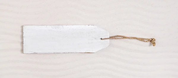 Old white wooden label or signboard in the beige sand. — Stock Photo, Image