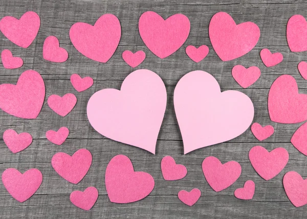 Roze hartjes op houten grijze shabby chic achtergrond. — Stockfoto