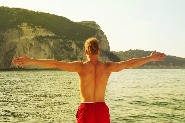 Hombre deportivo en el mar con los brazos extendidos. Pura libertad . — Foto de Stock