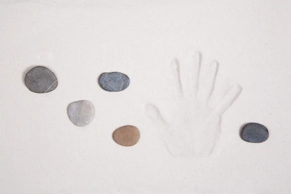 Hand afdrukken in het zand met vijf stenen voor meditatie concepten. — Stockfoto