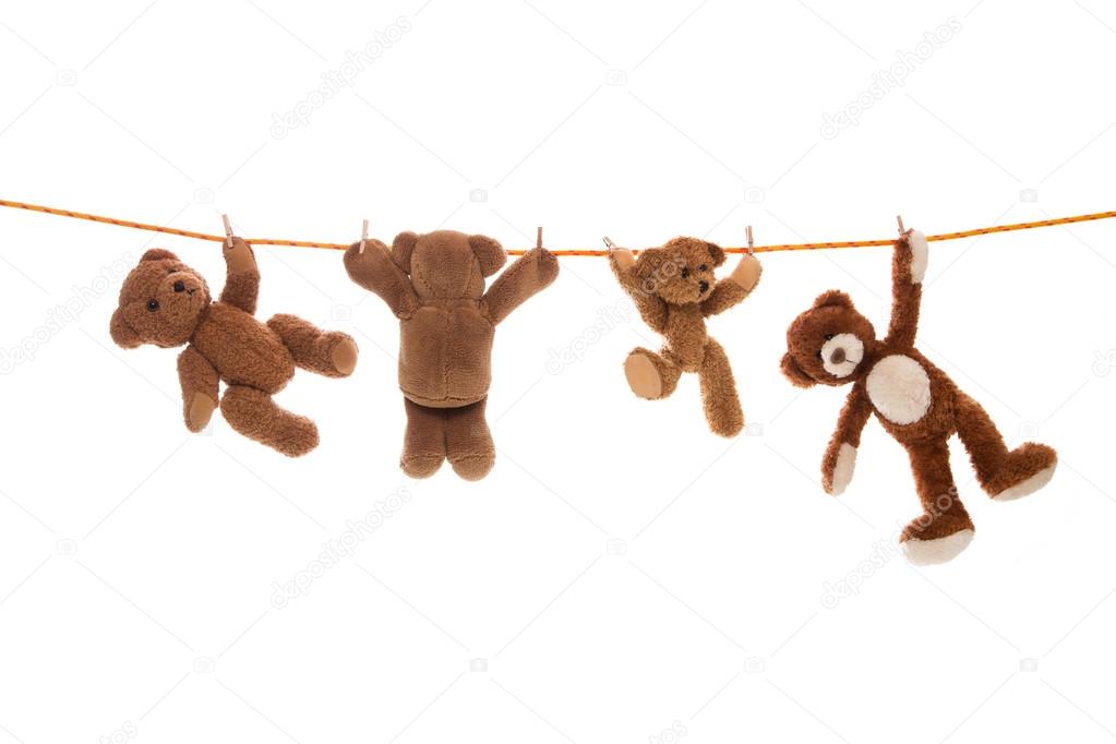 Hanging group of teddy bears on a clothing line with pegs.