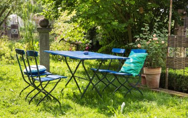 Nice relaxing place in the garden with blue furniture of wood.