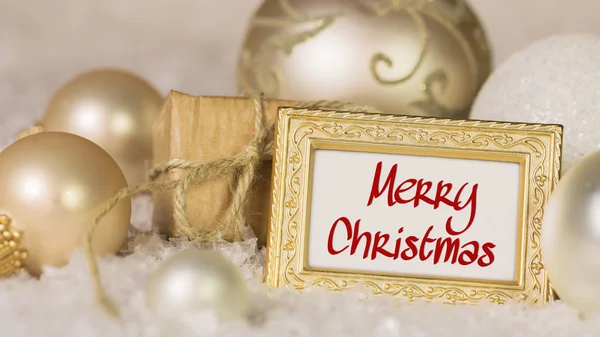 Bolas de Natal douradas e texto de saudação Feliz Natal . — Fotografia de Stock