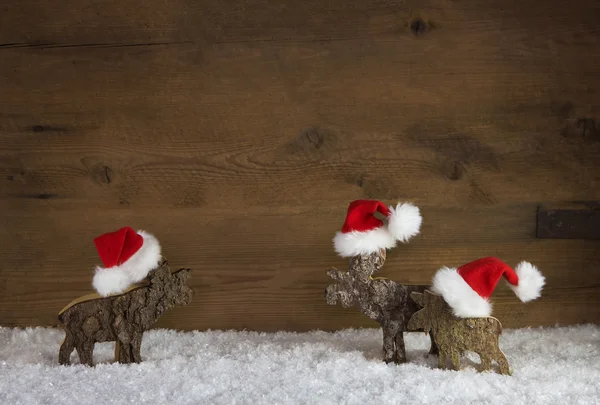 Tři Vánoční sobí ručně vyráběné dřevěné s červenou bílá santa h — Stock fotografie