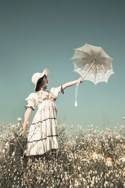 Happy young girl in country style dress stretching her hand with — Stock Photo, Image