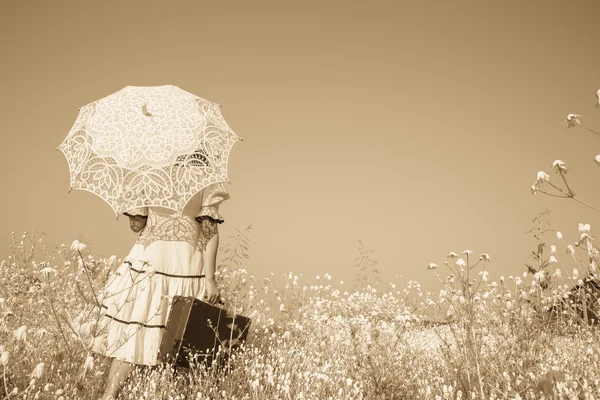 Nostalgic old photo in sepia color. Girl with her umbrella walki — 图库照片