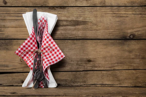 Fork and knife set with red white checked napkin on old rustic w 스톡 사진