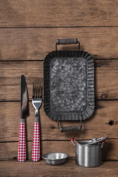 Cutlery in red white checked on an old wooden background with an — Stock Photo, Image