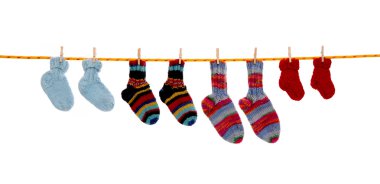 Four pairs of isolated handmade wool socks hanging on a rope.