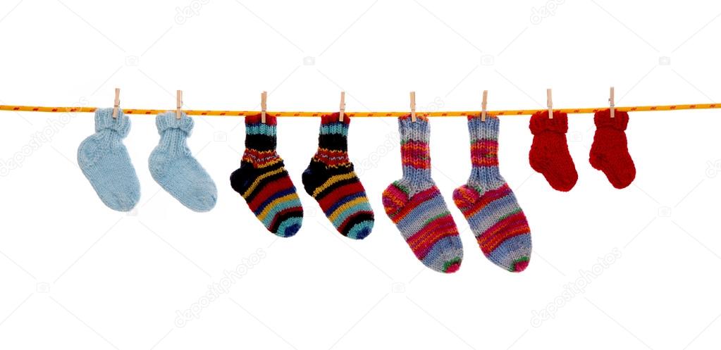 Four pairs of isolated handmade wool socks hanging on a rope.