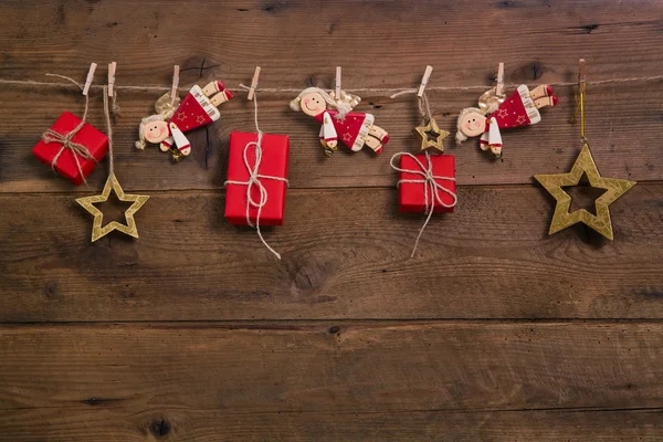 Red christmas presents with golden angels hanging on an old wood — Stok fotoğraf