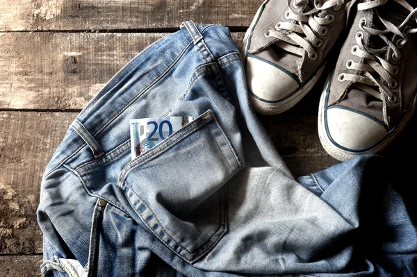 Dirty old jeans twenty euro bill and sneakers — Stock Photo, Image