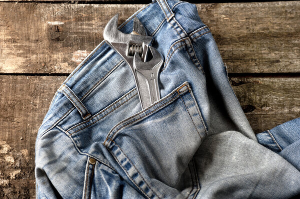 Грязные джинсы на полу с инструментами в кармане
